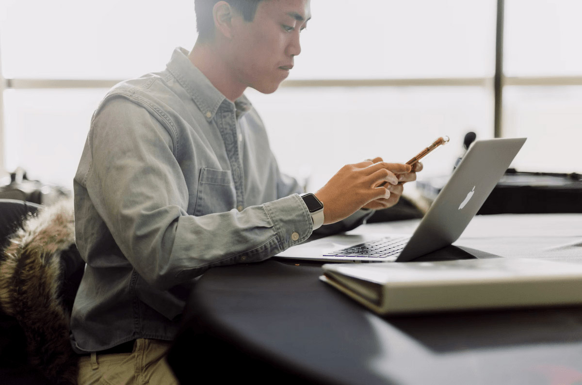 Person using phone and laptop